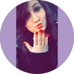 A woman with long dark hair blows a kiss towards the camera, showing her red-painted nails. The photo is framed within a circular border with a light purple background, capturing the warmth often found in Citrus Heights dental reviews.