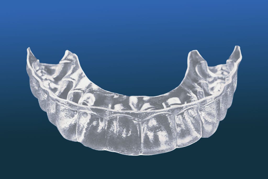 A clear, transparent dental aligner used in orthodontics is shown against a plain blue gradient background.