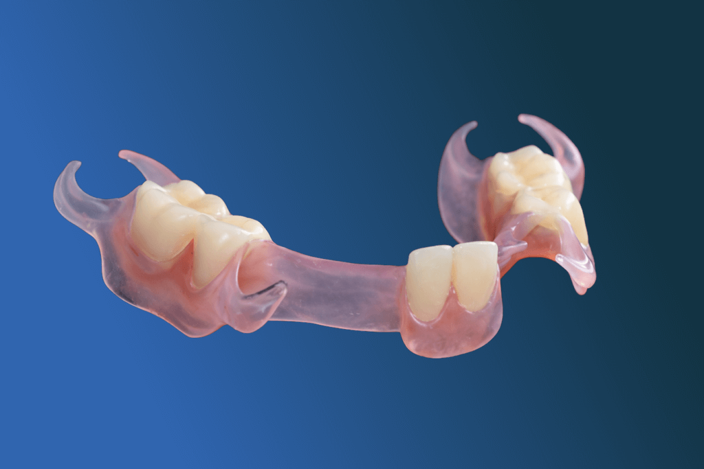 A flexible partial denture with pink gum-colored base and artificial teeth is shown on a blue gradient background. The denture features soft, curved clasps to fit around natural teeth.