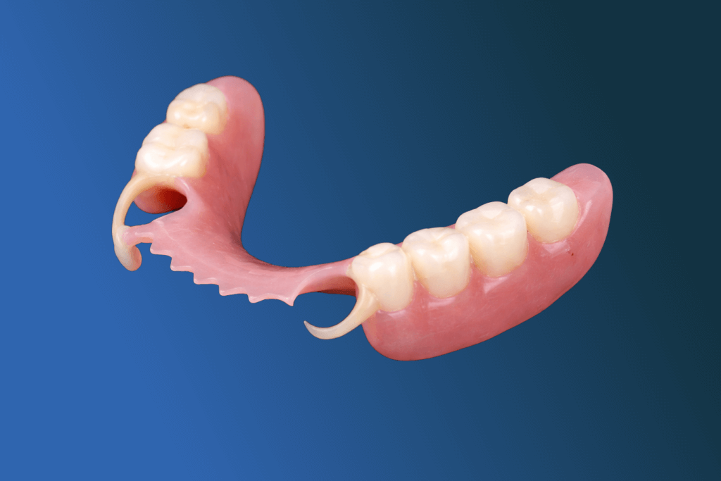 A partial denture with artificial teeth and pink gum base, designed to replace missing lower teeth, is shown on a blue gradient background.